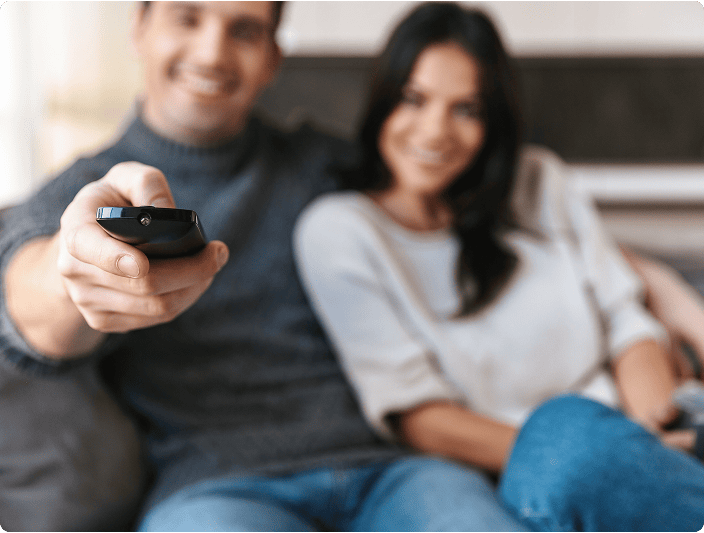 Fernsehmänner schauen entspannt Fernseher, während sie eine Fernbedienung in der Hand halten und gemeinsam Freizeit genießen. Perfekte Gelegenheit für Unterhaltung, Familie und gemütliche Abende zuhause.