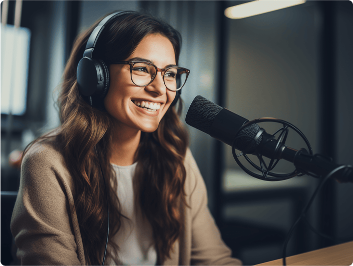 Junge Frau mit Kopfhörern beim Mikrofon in einem Radio- oder Podcaststudio, professionelle Aufnahmeumgebung, digitale Medien, Audioaufnahme, Moderatorin, kreative Produktion.